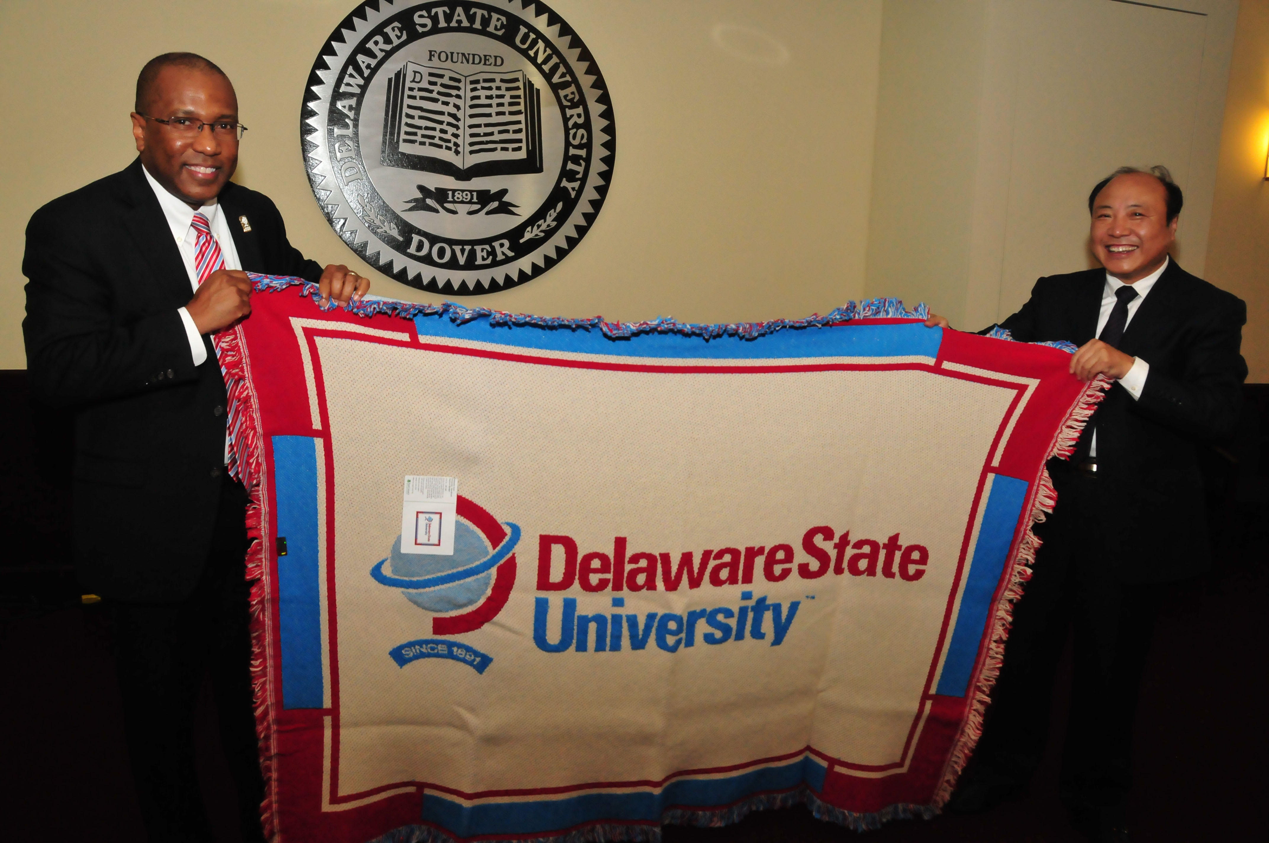 DSU Harry Williams presents a Del State blanket to Dr. Xiang Deming, Beihua VP of research, one of a number of gifts exchanged.