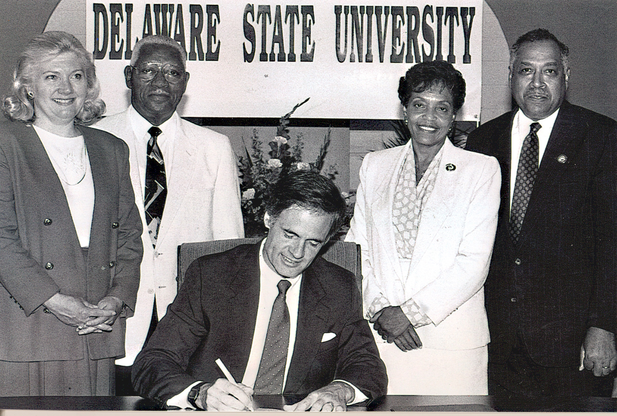 Dr. Willliam B. DeLauder (far right), the University's eighth president, stands with state Rep. Nancy Wagner, state Sen. Herman Holloway Sr., and his wife Vermell, as then-Gov Tom Carper signed legislation renaming the College to Delaware State University. Dr. DeLauder passed away on May 21.   