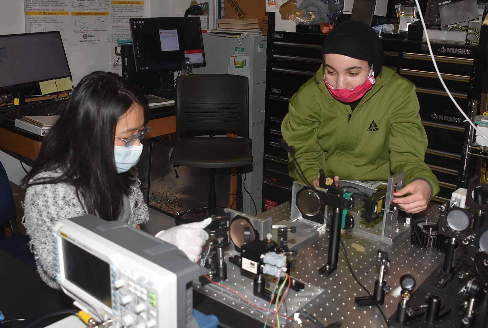 (L-r) Yue An, an optics graduate student from China, and Zayna Juracka, an engineering undergraduate and recent Early College High School graduate, are building a sensor that will measure air quality as part of an Air Quality Mapping summer program.