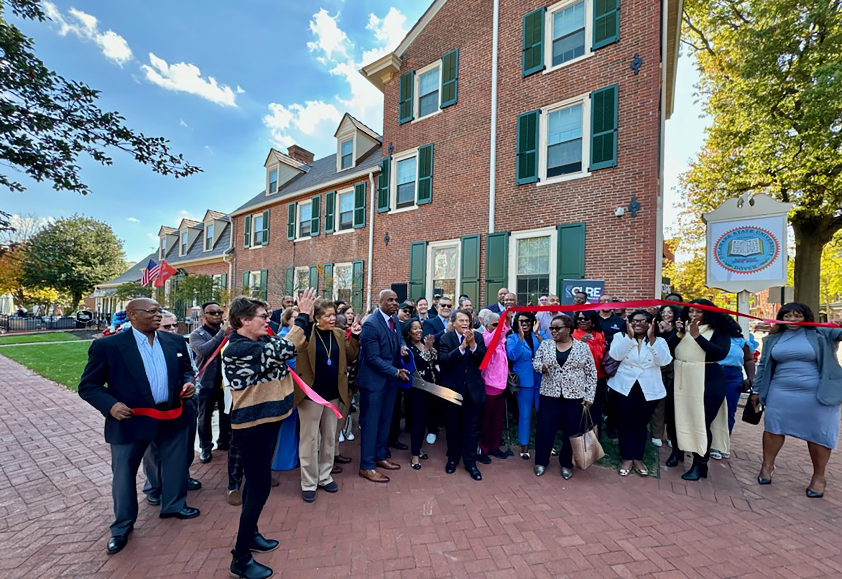 The attendees of the dedication ceremony for DSU's new CURE Loockerman Building erupt into a corporate cheer upon the cutting of the ribbon.