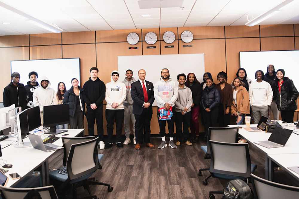 Greg Coverdale, Director of the Wealth Management Program, and new DSU Head Football Coach DeSean Jackson (both center) pose with a group of students after speaking to them about the importance of financial literacy.