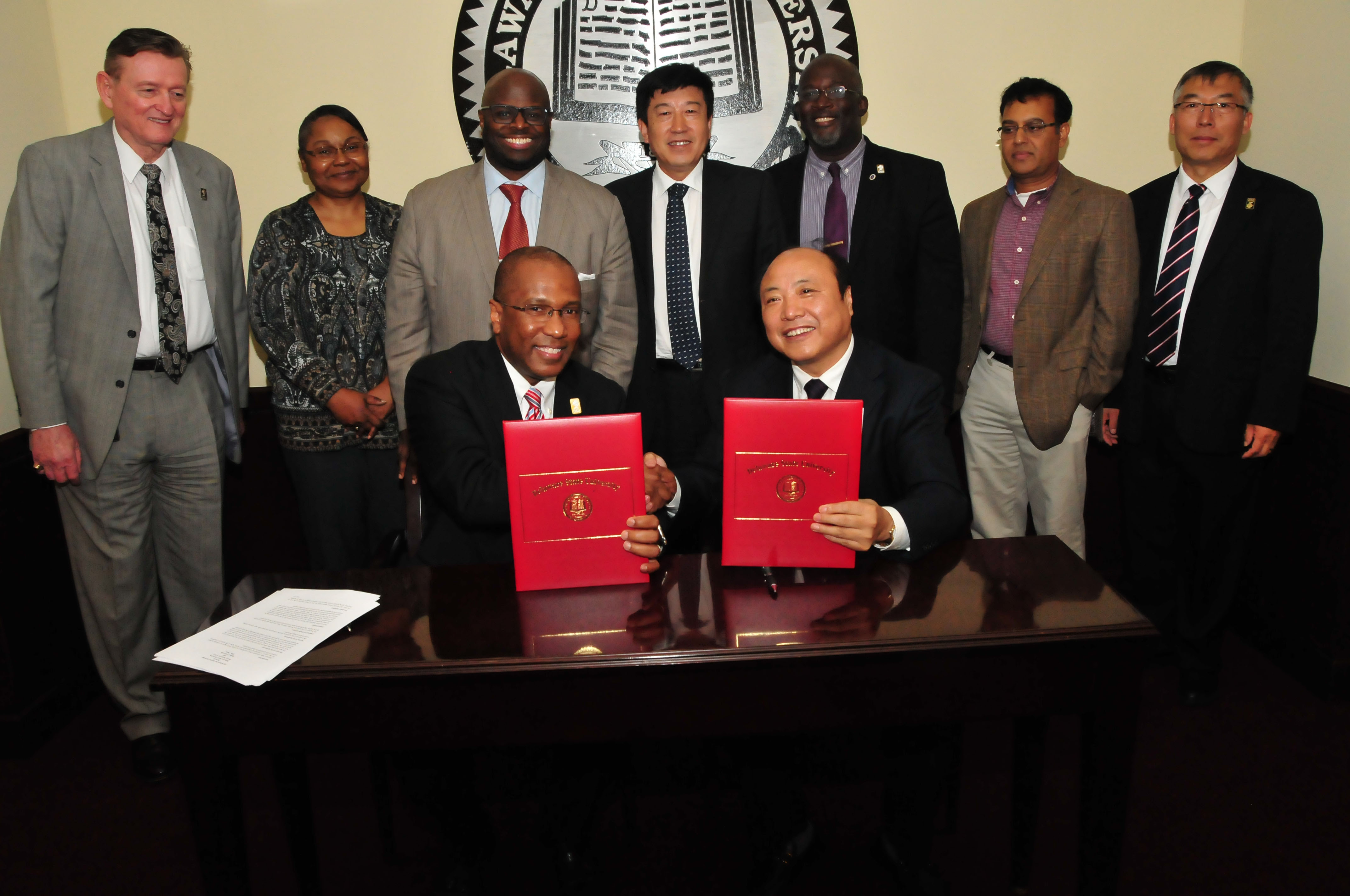 (Seated l-r) DSU President Harry L. Williams and Beihua University VP of Research Dr. Xiang Deming shake hands and hold a joint agreement concerning study abroad opportunities. (Standing l-r) Associate Provost Brad Skelcher, Vice Provost Saundra DeLauder, Provost Tony Allen, Interim Dean Charlie Wilson (College of Mathematics, Natural Sciences and Technology), Dr. Mukti Rana, chair of the Department of Physics and Pre-Engineering, and International Affairs Associate Vice President Fengshan Liu.